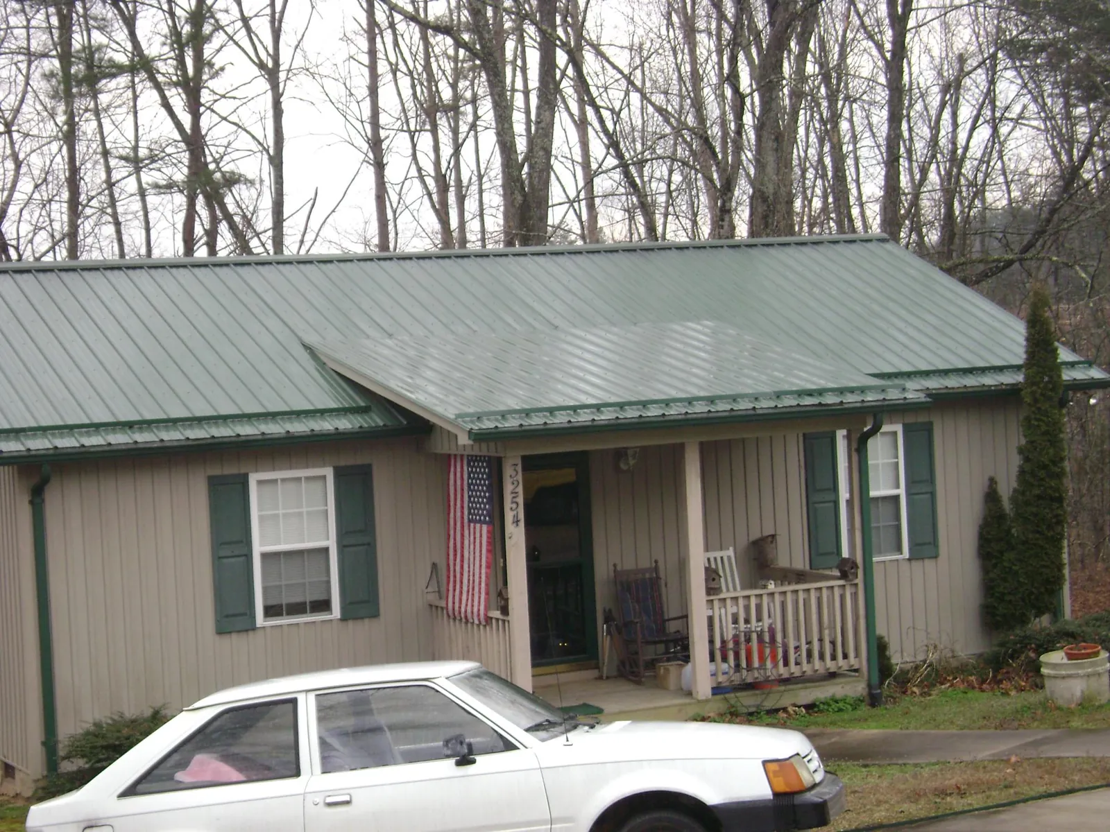 Green metal roof and front porch on a tan sided cottage in Fairfield